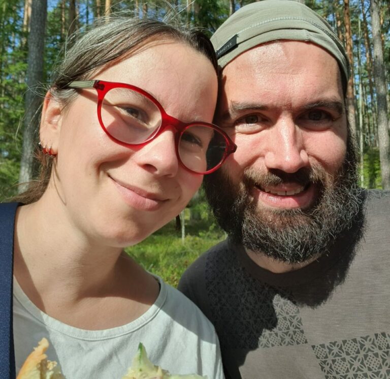Kurser och undervisning 2 Porträtt på Nina och Thomas i en tallskog i solen. Båda ler och tittar in i kameran. Nina bär röda glasögon, Thomas har skägg.