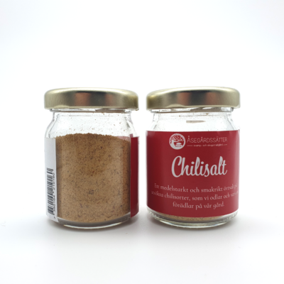 två burkar chilisalt, en sett från framsidan med etiketten, en bakifrån. saltet har en rödbrun färg.